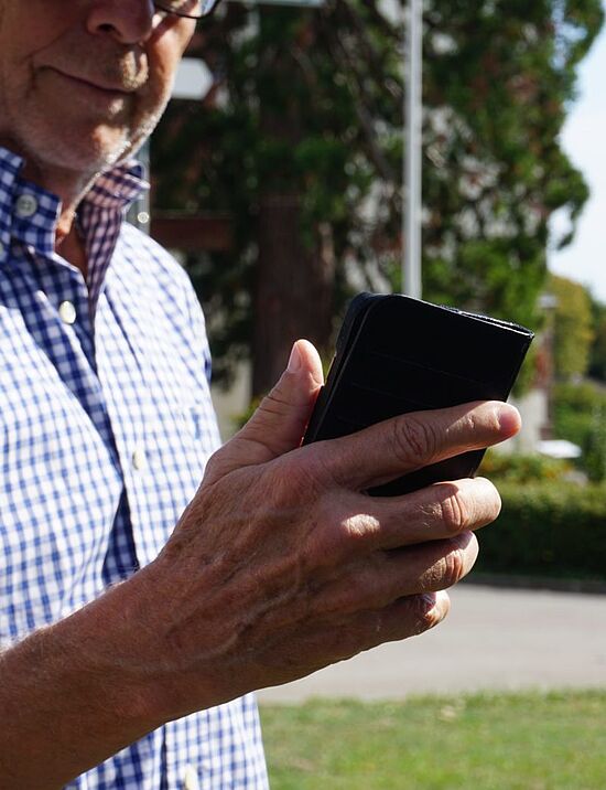 aged man holding smartphone